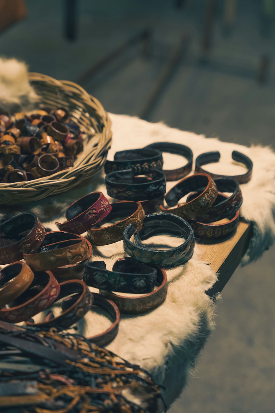 Braccialetti e anelli in pelle fatti a mano esposti su pelliccia bianca.